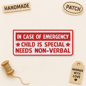 May include: A rectangular embroidered patch with the text "IN CASE OF EMERGENCY CHILD IS SPECIAL NEEDS NON-VERBAL" in red and white. The patch has a red border. Other tags and patches with "HANDMADE" and "PATCH" are also visible.