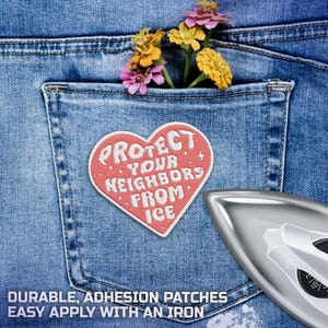 K&ouml;nnte beinhalten: Ein herzf&ouml;rmiger Aufn&auml;her mit dem Text "PROTECT YOUR NEIGHBORS FROM ICE" ist auf einer Jeans-Tasche angebracht. Die Tasche enth&auml;lt Blumen. Ein B&uuml;geleisen befindet sich in der unteren rechten Ecke.