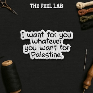 May include: A black background with the text "THE PEEL LAB" at the top. The text "I want for you whatever you want for Palestine" is embroidered in white. Sewing supplies, including thread, scissors, and a needle, are arranged around the text.