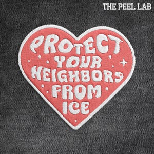 May include: Embroidered heart-shaped patch with the text "PROTECT YOUR NEIGHBORS FROM ICE" in white thread. The heart is red with a white border, set against a dark grey fabric background. The text "THE PEEL LAB" is at the top.