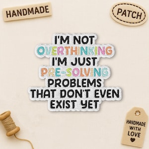 May include: Embroidered patch with the text "I'M NOT OVERTHINKING I'M JUST PRE-SOLVING PROBLEMS THAT DON'T EVEN EXIST YET." The patch has a white border and colorful text. Also shown are tags that say "HANDMADE" and "HANDMADE WITH LOVE".
