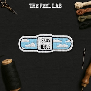 May include: Embroidered patch in the shape of a bandage, featuring a blue sky with white clouds and the text "JESUS HEALS". The patch is surrounded by a white border and the text "THE PEEL LAB" is at the top.