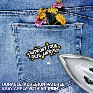 May include: Close-up of a denim pocket with a patch that reads "Support Your Local Library." The pocket contains colorful flowers. A silver iron is in the lower right corner. The text "Durable, Adhesion Patches, Easy Apply With An Iron" is at the bottom.