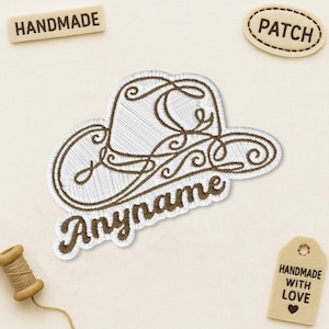 May include: An embroidered patch featuring a white cowboy hat outline with brown swirling decorative lines and the brown cursive text "Anyname" underneath. The patch is surrounded by small labels reading "HANDMADE", "PATCH", and "HANDMADE WITH LOVE".