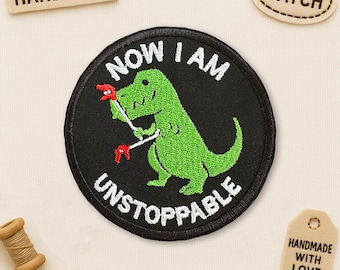 May include: Embroidered patch with a green dinosaur holding red tools, surrounded by the words "NOW I AM UNSTOPPABLE" in white on a black background. Includes a "PATCH" and "HANDMADE" tag.