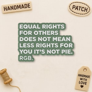 May include: A collection of handmade patches and tags on a cream fabric. The central green patch features white embroidered text: "EQUAL RIGHTS FOR OTHERS DOES NOT MEAN LESS RIGHTS FOR YOU IT'S NOT PIE. RGB." Other tags say "HANDMADE" and "PATCH."