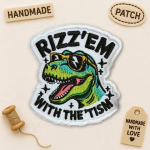 May include: Embroidered patch with a green and blue dinosaur wearing sunglasses, and the text "Rizz'em With The Tism". The patch has a white border. Wooden tags read "Handmade" and "Patch".
