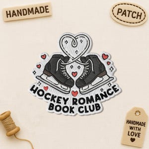 Puede incluir: Parche bordado con dos patines de hielo negros formando un coraz&oacute;n, con el texto "HOCKEY ROMANCE BOOK CLUB". El parche incluye peque&ntilde;os corazones rojos y la palabra "PATCH" en una etiqueta separada.