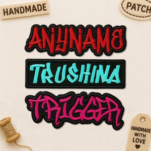 May include: Three embroidered patches with text in a graffiti style. The top patch reads "ANYNAME" in red with a black outline. The middle patch reads "TAUSHINA" in turquoise on a black background. The bottom patch reads "TRIGGER" in pink with a black outline.