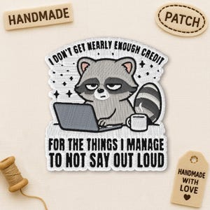 May include: Embroidered patch with a cartoon raccoon using a laptop and a coffee cup, with the text "I DON'T GET NEARLY ENOUGH CREDIT FOR THE THINGS I MANAGE TO NOT SAY OUT LOUD." Includes "HANDMADE" and "PATCH" tags.