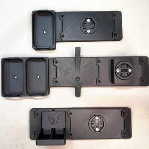 May include: Three black matte 3D-printed mounts with integrated circular locking mechanisms. The top mount has one rectangular compartment, the middle has two, and the bottom has a small dual-bin section. Each features the VF logo embossed.