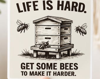 May include: A square sticker with a cream background featuring a black ink illustration of a wooden beehive on a stand with three bees flying around it. The text reads: LIFE IS HARD. GET SOME BEES TO MAKE IT HARDER. The sticker has rounded corners.