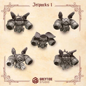 May include: Five gray jetpacks with intricate details, including wings and skull motifs. The text "Jetpacks 1" is at the top, and the "GREYTIDE STUDIO" logo is at the bottom. These miniature models are likely for tabletop gaming or hobby projects.