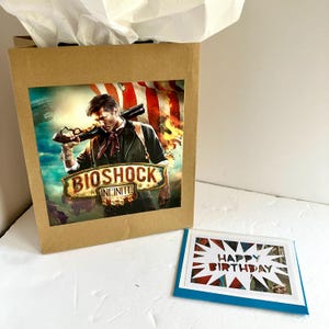 Sacola de presente e cartão comemorativo do livro BioShock Infinite