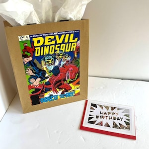 Sacola de presente e cartão comemorativo em quadrinhos do Diabo Dinossauro