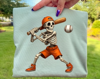May include: A light blue fabric with a baseball-themed illustration. The illustration features a skeleton wearing an orange baseball cap and shorts, holding a bat, with a baseball in the air. The text "PNG INSTANT DOWNLOAD PNG" is at the bottom.