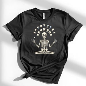 May include: Black t-shirt with a skeleton meditating, encircled by teeth and dental instruments. The skeleton holds a dental probe and mirror. A humorous design related to dentistry.
