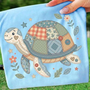 May include: A light blue fabric with a patchwork turtle design. The turtle features a patterned shell with various fabrics, decorative buttons, and a smiling face. Surrounding the turtle are stars, flowers, and leaves.