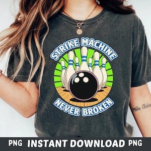 Peut inclure: T-shirt gris foncé avec un motif sur le thème du bowling. Le motif comprend des quilles, une boule de bowling noire et le texte "STRIKE MACHINE NEVER BROKEN" dans une disposition circulaire. Vêtement décontracté.