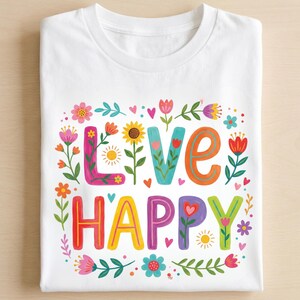 K&ouml;nnte beinhalten: Wei&szlig;es T-Shirt mit einem farbenfrohen Blumendesign und den Worten "LIVE HAPPY" in lebendigen, verspielten Buchstaben. Das Design umfasst Blumen, Herzen und Bl&auml;tter in verschiedenen Farben und schafft eine fr&ouml;hliche und erhebende &Auml;sthetik.