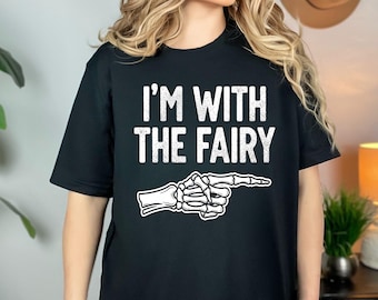 May include: Black t-shirt with the white text "I'M WITH THE FAIRY" and a skeleton hand pointing to the right. The shirt is a short-sleeved crew neck.