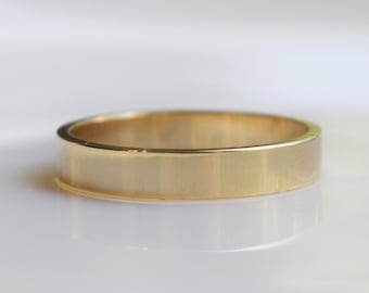 May include: A simple gold band ring with a smooth, polished finish.