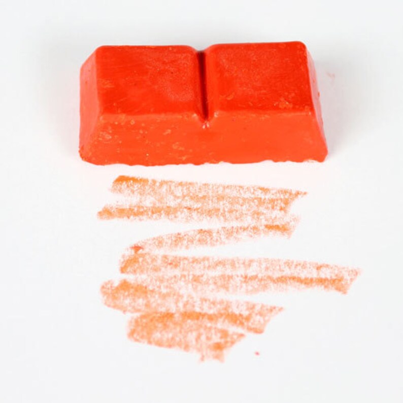 May include: A bright orange crayon with a rectangular shape and a slight indentation in the middle. The crayon has been used to draw several orange lines on a white surface.