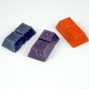 May include: Three rectangular blocks of wax in different colors: teal, purple, and orange. The blocks are slightly textured and have a slight sheen.