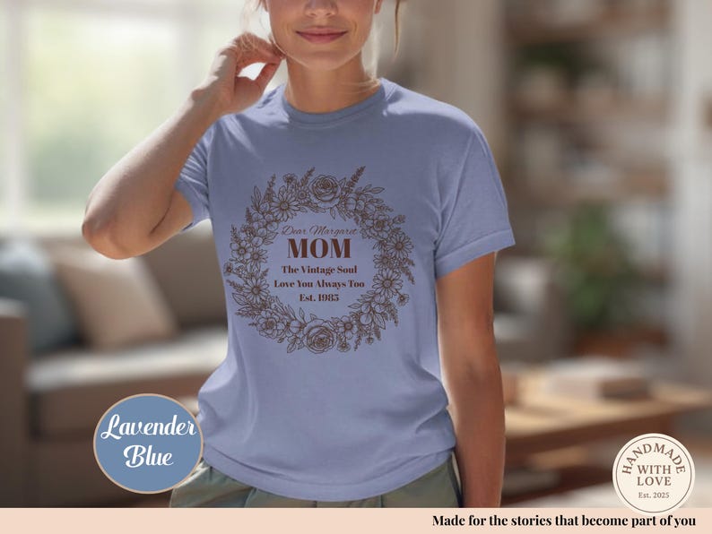 Pu&ograve; includere: T-shirt blu lavanda con un design a ghirlanda floreale e la scritta "Dear Margaret MOM The Vintage Soul Love You Always Too Est. 1983". La maglietta ha anche un logo "Handmade with Love".