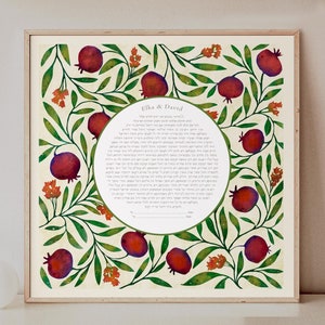 May include: A square framed print featuring a central circular area containing Hebrew text and the names Elka & David. The surrounding border is decorated with a botanical pattern of green leaves, small orange flowers, and deep red pomegranates.