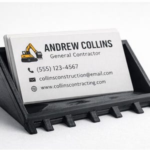 Puede incluir: Un tarjetero negro con una pila de tarjetas de visita blancas. Las tarjetas muestran el nombre "Andrew Collins, Contratista General", información de contacto y un pequeño gráfico de excavadora.