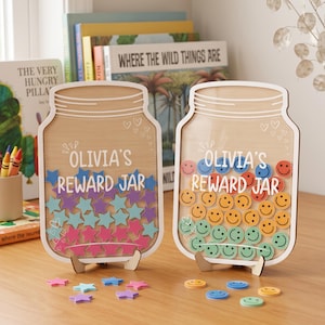 May include: Two wooden reward jars shaped like mason jars, each featuring the text 'OLIVIA'S REWARD JAR'. One jar is filled with colorful star-shaped tokens, while the other contains circular tokens with smiley face designs. Both jars stand on small wooden bases.