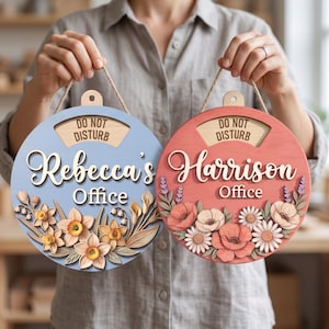May include: Two circular wooden door signs with jute rope hangers. The blue sign features the text "Rebecca's Office" and "DO NOT DISTURB" with yellow daffodils. The coral sign features "Harrison's Office" and "DO NOT DISTURB" with pink and white flowers.