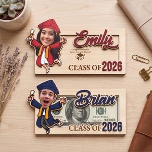 May include: Two personalized graduation photo frames. One features a cartoon image of a graduate in a red cap and gown, the name "Emily", and "Class of 2026". The other frame has a cartoon graduate in a blue cap and gown, the name "Brian", and "Class of 2026".
