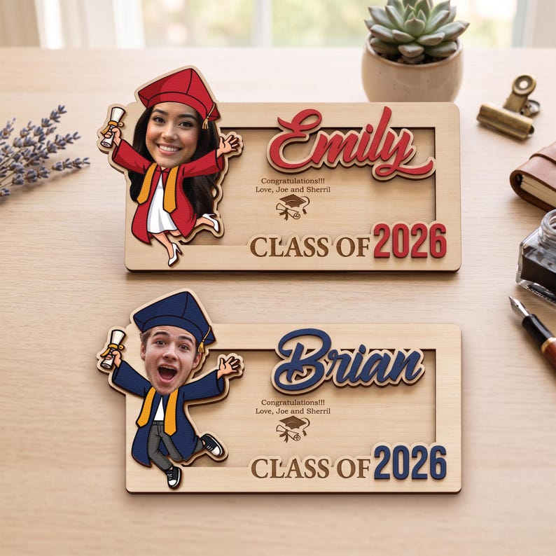 May include: Two wooden graduation photo frames. One frame features the name "Emily" in red script, the text "Class of 2026", and a cartoon image of a graduate. The other frame has the name "Brian" and the same text and cartoon image.