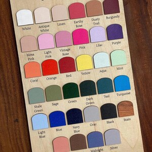 May include: Wooden paint color chart with the text "Paint Options." The chart displays a variety of paint colors, including white, pink, blue, green, and brown. Each color is labeled with its name, such as "White," "Pink," and "Blue."
