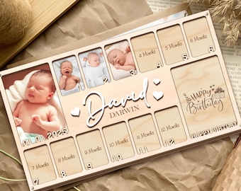 May include: Wooden baby milestone photo frame with spaces for photos from 1 to 12 months, plus a space for a birth photo. The frame includes the name "David Darwin" and "Happy Birthday" text.