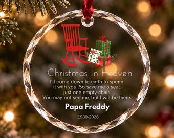 Può includere: Una decorazione natalizia circolare in vetro trasparente con un nastro rosso. Presenta una sedia a dondolo rossa, regali verdi e bianchi, e il testo: Christmas In Heaven, I'll come down to earth to spend it with you. So save me a seat, just one empty chair. You may not see me, but I will be there. Papa Freddy 1930-2026.