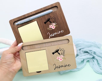 May include: Two wooden desk organizers, one dark brown and one light brown, each with a slot for a notepad and a pen. The organizers feature a floral design with a hairdryer and scissors, and the name "Jasmine".