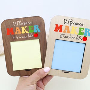 May include: Two wooden memo holders with the text "Difference Maker" in colorful letters and the hashtag "#teacher life." One holder is dark brown, the other is light wood. Each has a space for a note or photo and a small red apple graphic.