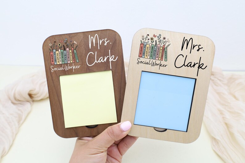 A person's hand is holding two wooden frames with names on them.
