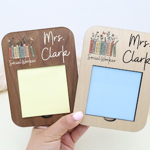 A person's hand is holding two picture frames, each with a name tag on the front. The name tags are labeled "Mrs. Clark" and "Mrs. Clark Social Worker".