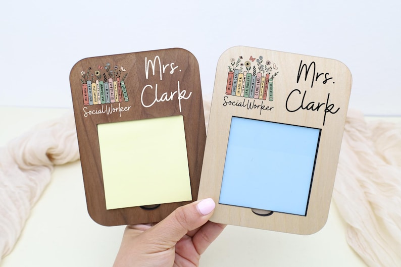 A person's hand is holding two picture frames, each with a name tag on the front. The name tags are labeled "Mrs. Clark" and "Mrs. Clark Social Worker".