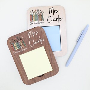 two wooden name cards, each with a name written on it, and a pen is placed next to them.