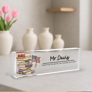 A clear glass block with a stack of books and an American flag on it, placed on a table.