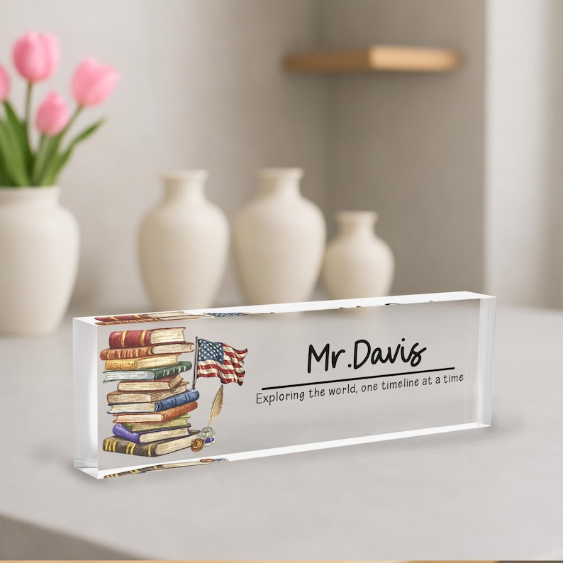 A clear glass block with a stack of books and an American flag on it, placed on a table.