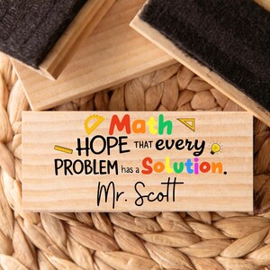 Puede incluir: Un letrero rectangular de madera con las palabras "Math, HOPE that every PROBLEM has a Solution. Mr. Scott" en texto colorido. El letrero incluye acentos amarillos, verdes, naranjas y azules. Tambi&eacute;n se incluye una regla y un transportador.