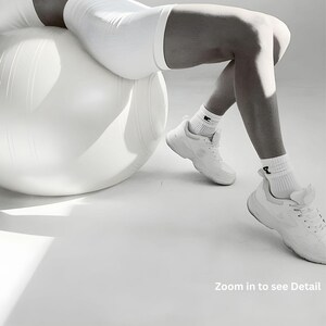 May include: A white exercise ball with a person wearing white athletic shorts, socks, and sneakers. The image has the text "Zoom in to see Detail".