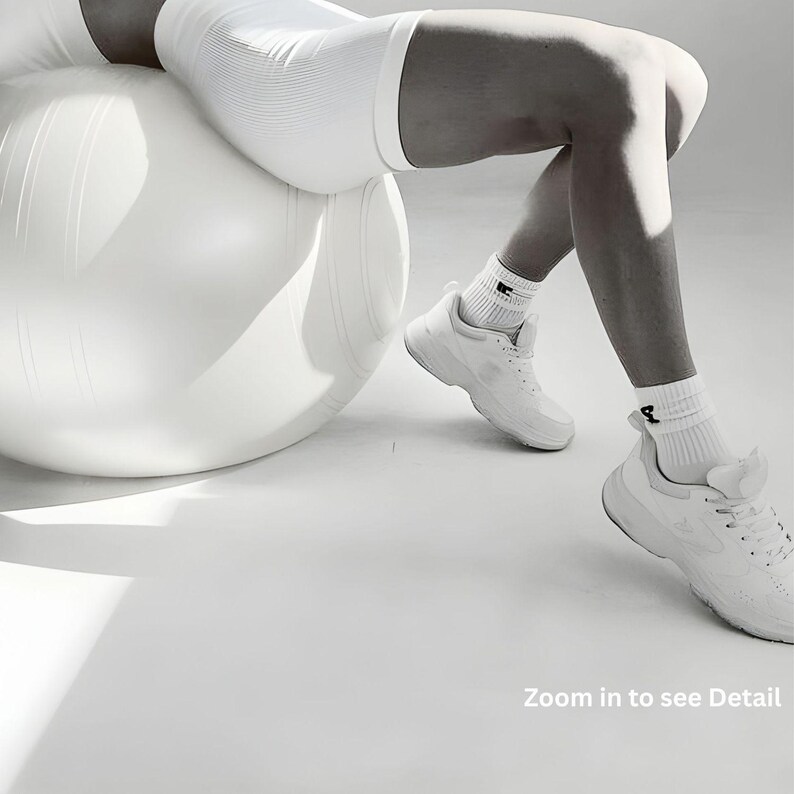 May include: A white exercise ball with a person wearing white athletic shorts, socks, and sneakers. The image has the text "Zoom in to see Detail".
