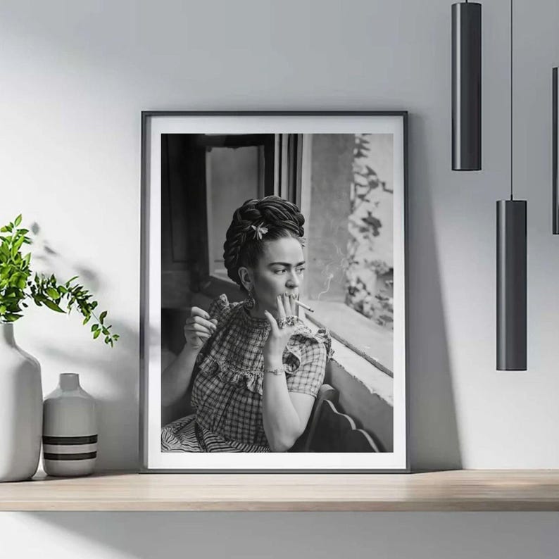 Pu&ograve; includere: Stampa incorniciata in bianco e nero di una donna che fuma una sigaretta. La donna indossa un top a quadri e ha i capelli raccolti in uno chignon con un fiore. La stampa &egrave; esposta su una mensola di legno con un vaso e illuminazione decorativa.